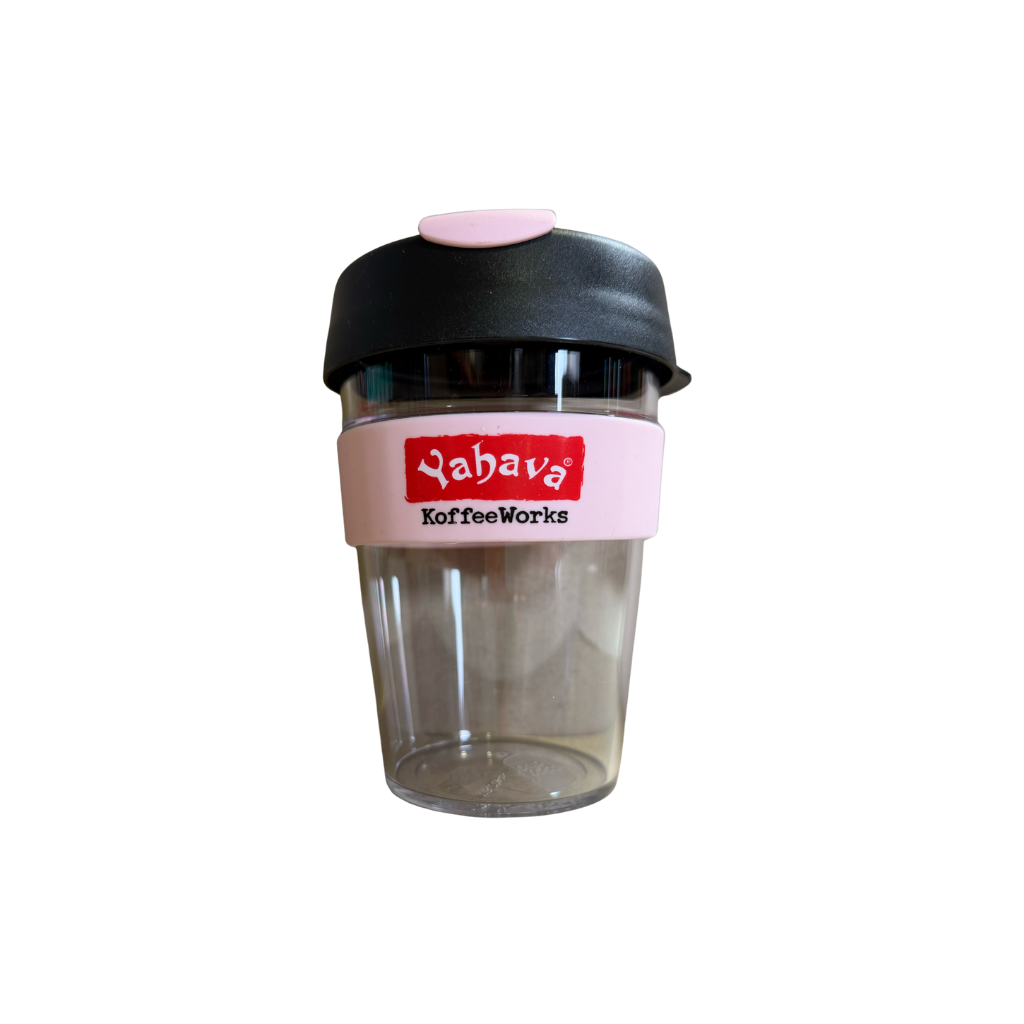 A reusable travel tumbler with a clear plastic body, a black lid with a pink top cap, and a pink silicone band featuring the red and white 'Yahava KoffeWorks' logo.