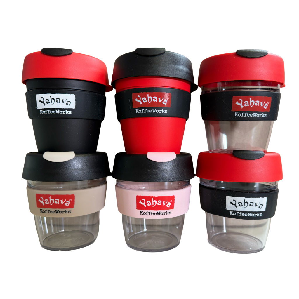 Six reusable travel coffee cups from Yabava Koffee Works arranged in a 3x2 grid on a plain white background. The cups feature different color combinations: red and black lids/cups, red and black cups with white labels, red and black cups with beige labels, red and black cups with pink labels, red and black cups with white labels, and red and black cups with beige labels.