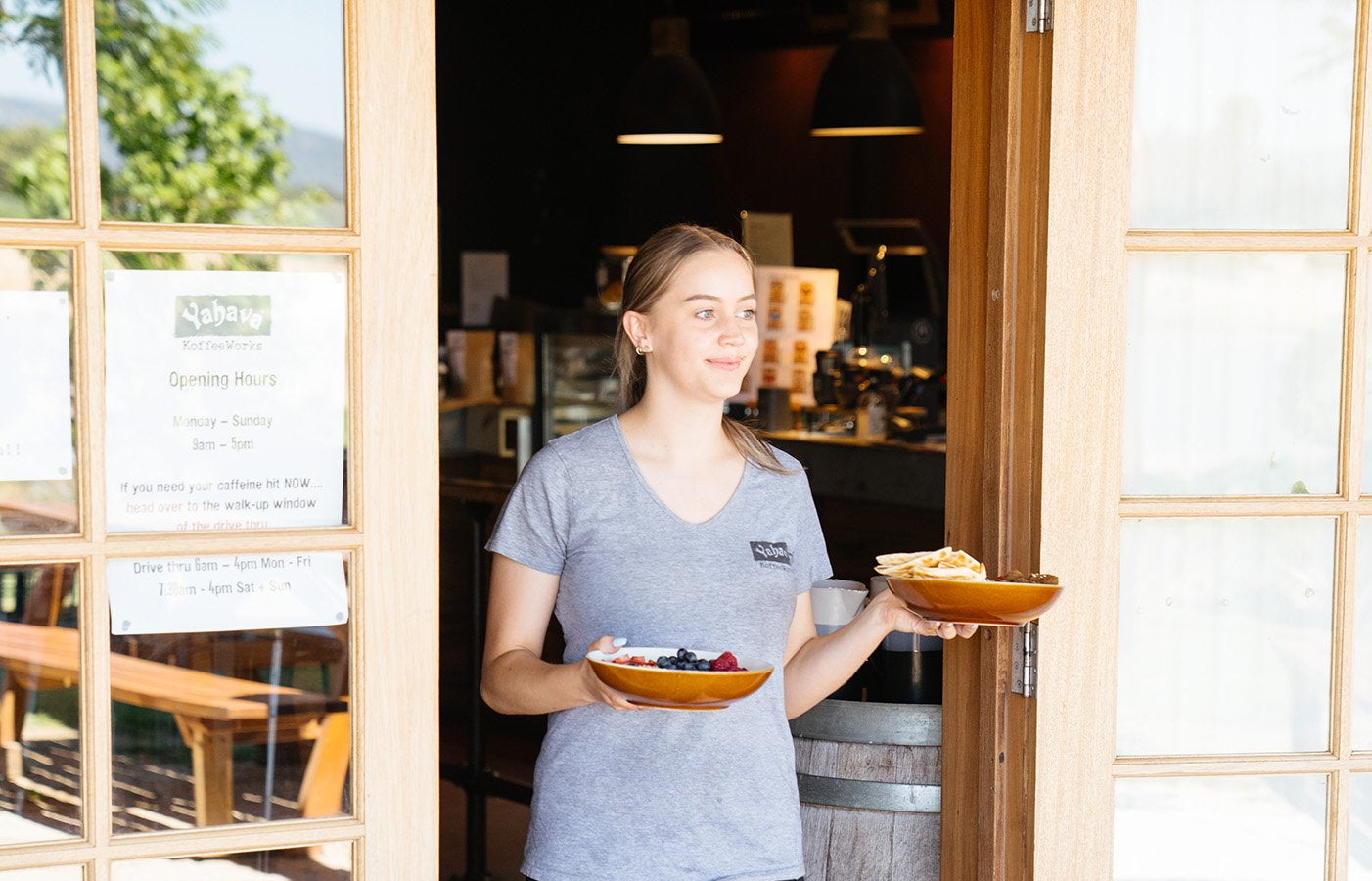 Staff member holding two bowls of food at a cafe entrance